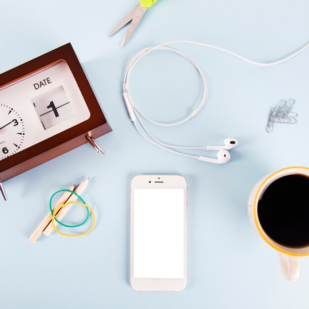 Coffee and smartphone near stationery and clock