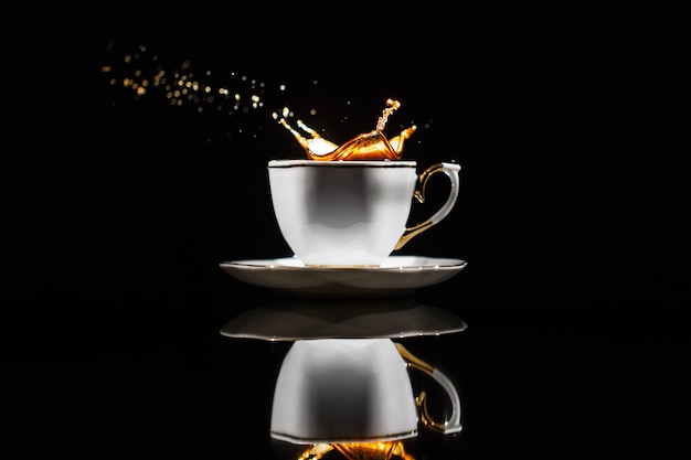 Foto gratuita il caffè spruzza in tazza bianca su priorità bassa nera