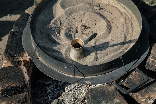 Free photo coffee in a turk on the sand, making turkish coffee.