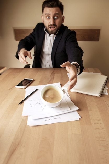 사무실 테이블에서 아침 근무일에 테이블에 쏟아지는 흰색 컵에 커피