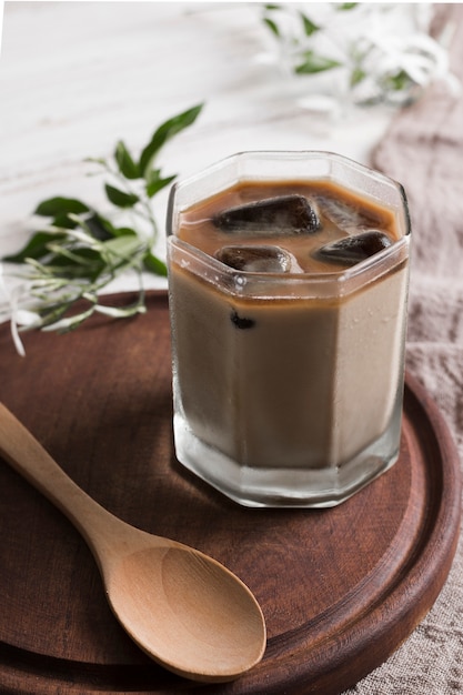 Coffee with ice cubes in glass and wooden spoon