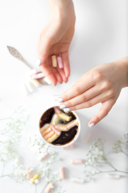 Caffè con marshmallow e mani delle donne la vista dall'alto