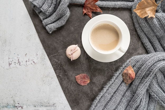 Coffee with milk and warm sweater on shabby surface