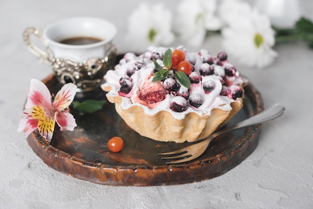 Coffee with tasty fruit tart and flowers on wooden tray