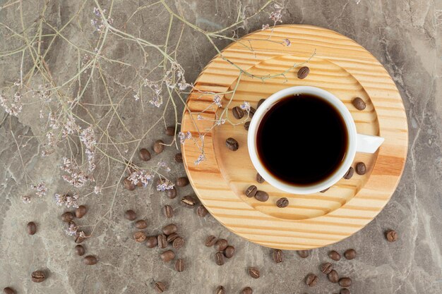 Кофе на деревянной тарелке с кофейными зернами.