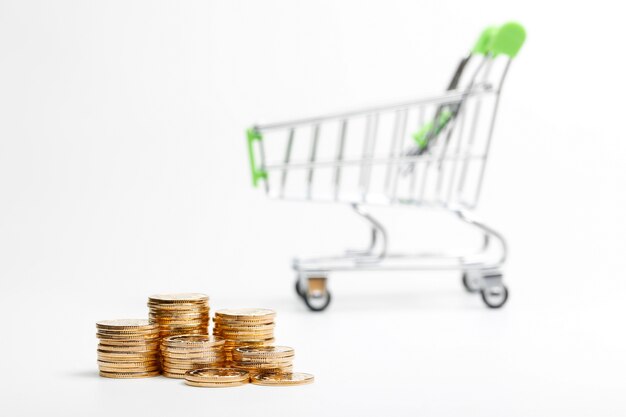 COINS pile and shopping cart on a white background