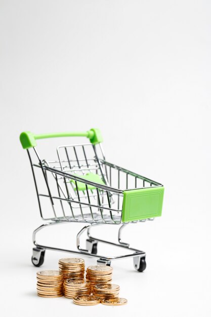 COINS pile and shopping cart on a white background