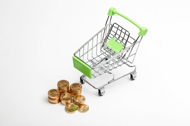 COINS pile and shopping cart on a white background