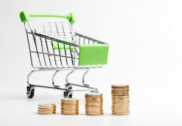 Free photo coins pile and shopping cart on a white background