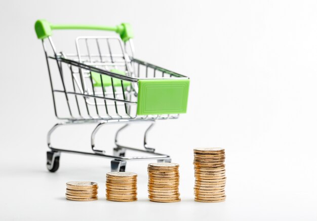 COINS pile and shopping cart on a white background