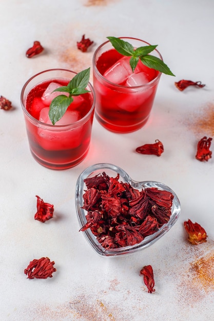 Cold brew hibiscus tea with ice and basil leaves.