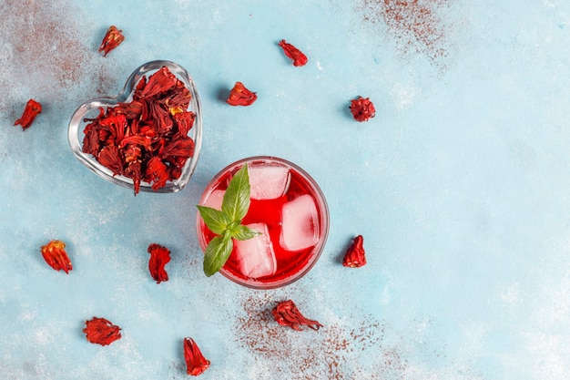 Cold brew hibiscus tea with ice and basil leaves.