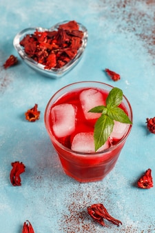 Cold brew hibiscus tea with ice and basil leaves.