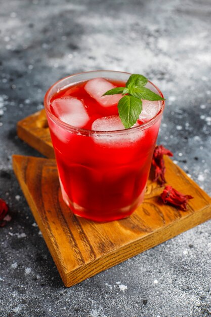 Cold brew hibiscus tea with ice and basil leaves.