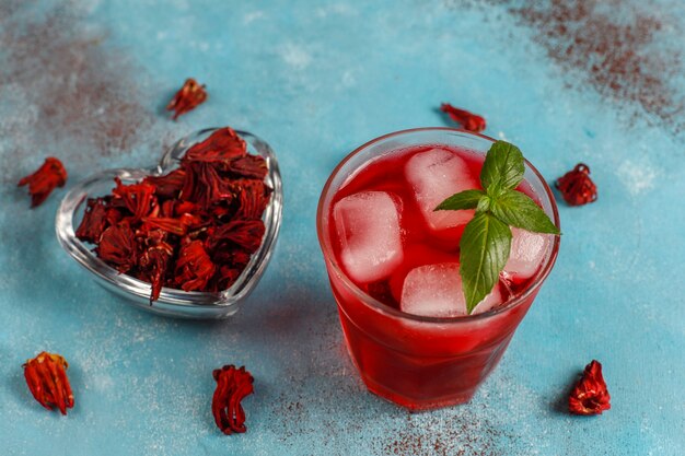 Cold brew hibiscus tea with ice and basil leaves.