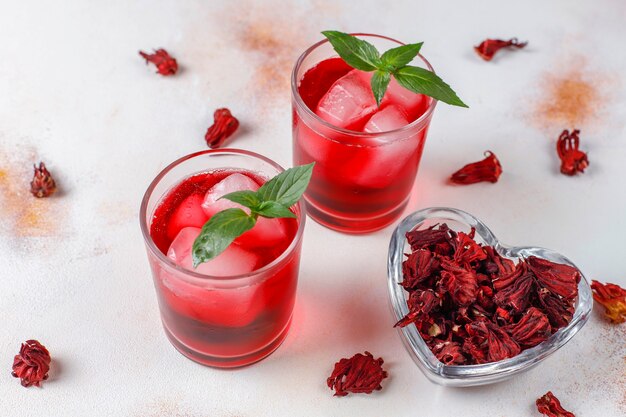 Cold brew hibiscus tea with ice and basil leaves.