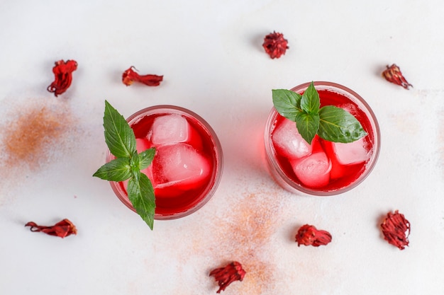 Cold brew hibiscus tea with ice and basil leaves.