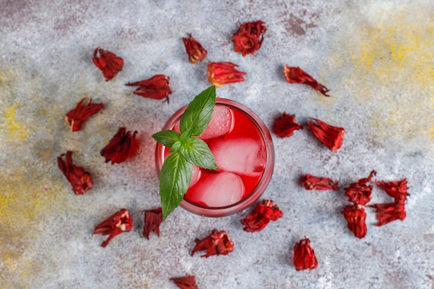 Cold brew hibiscus tea with ice and basil leaves.