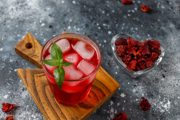 Cold brew hibiscus tea with ice and basil leaves.