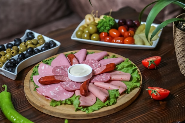 Free photo cold cuts and pickles sausages ham olives tomato cucumber side view