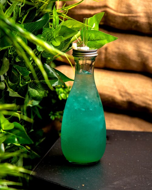 Cold drink with ice turquoise in a glass bottle