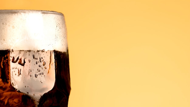 Free photo cold glass of beer on yellow background