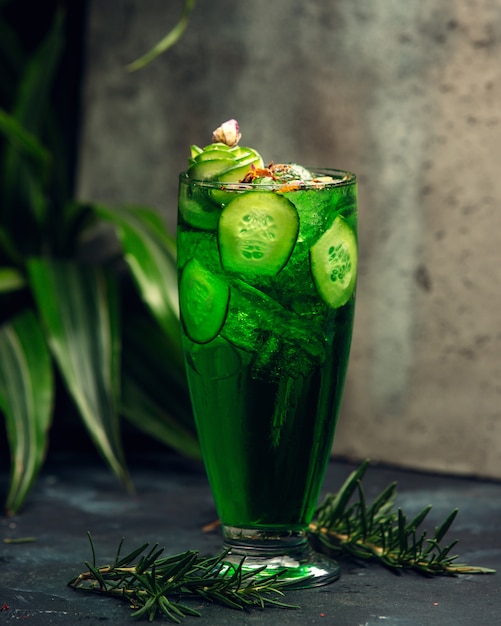 Cold green drink in a glass with sliced cucumber slices