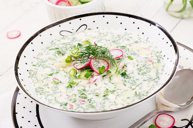 Холодный суп со свежими огурцами, редис с йогуртом в миску на деревянный стол. Традиционная русская еда - окрошка. Вегетарианская еда.