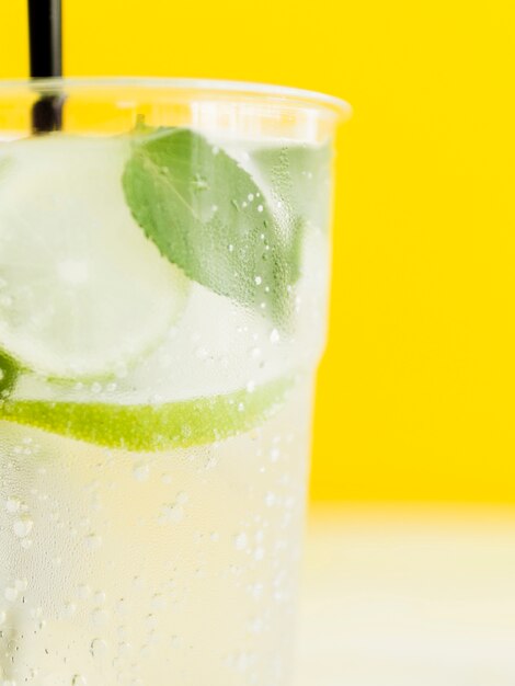 Free photo cold white tasty cocktail with lime, mint and ice on yellow background