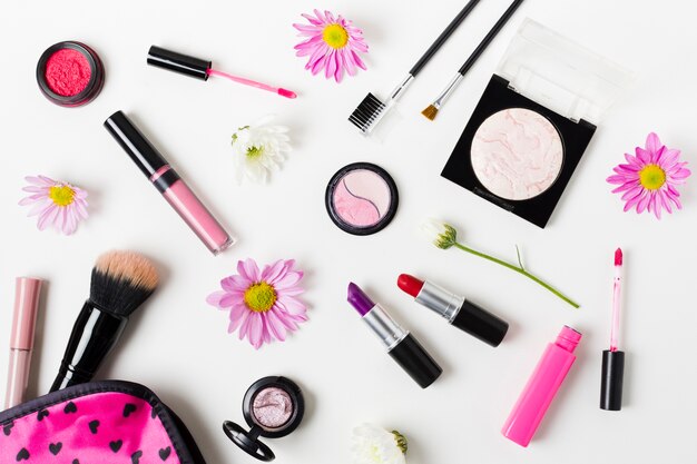 Collage of feminine colourful cosmetics on white desk