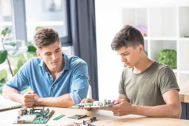 Colleague looking at IT engineer repairing pc motherboard