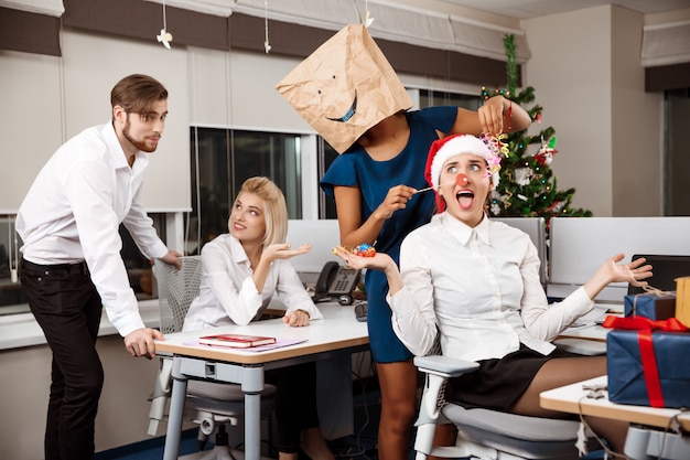 Colleagues celebrating christmas party in office drinking champagne smiling.