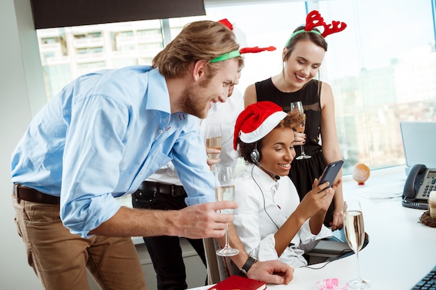 Free photo colleagues celebrating christmas party in office drinking champagne smiling.