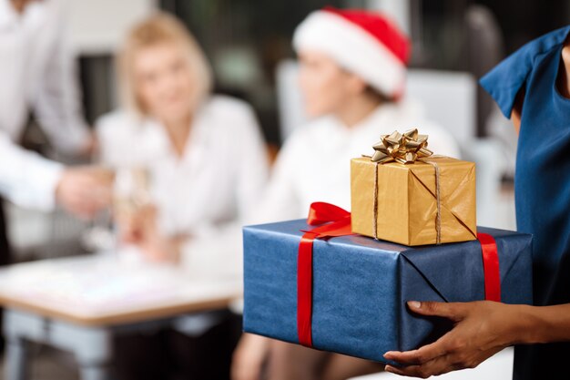 Colleagues celebrating christmas party in office smiling giving presents.