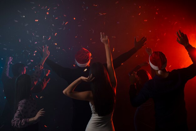 Коллеги танцуют в конфетти на новогодней вечеринке