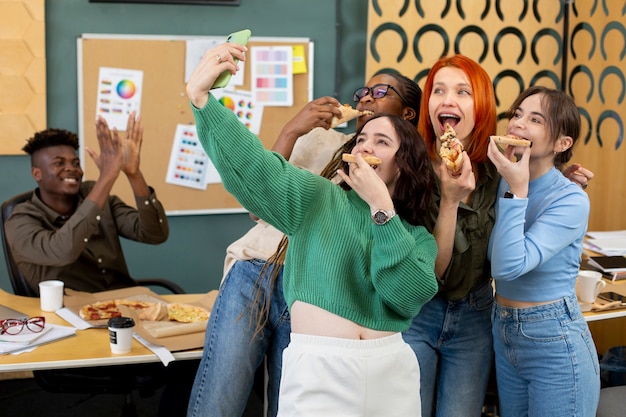 Foto gratuita colleghi che mangiano pizza al lavoro a tiro medio