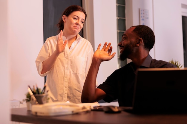 Free photo colleagues giving high five, celebrating success, coworkers teamwork, man and woman working on laptop in office at night. two employees checking company report together in coworking space