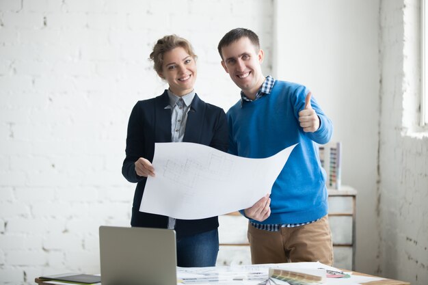 Colleagues holding finished architectural blueprints