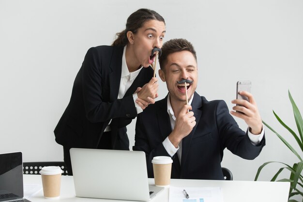 Colleagues making self-portrait with mustache accessory