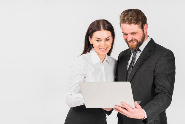 Colleagues male and female smiling and looking at laptop