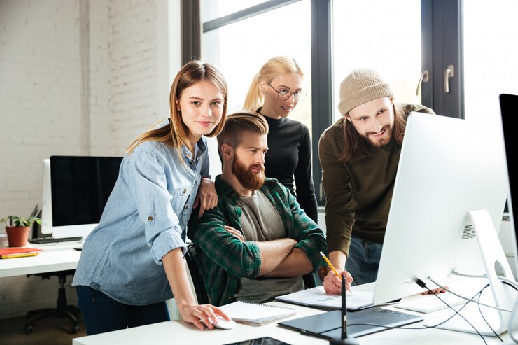 Free Photo colleagues in office talking with each other using computer.