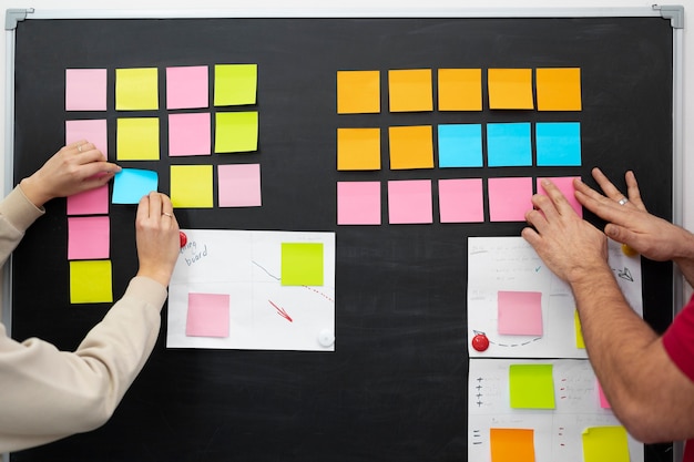 Free photo colleagues sticking colorful post its together