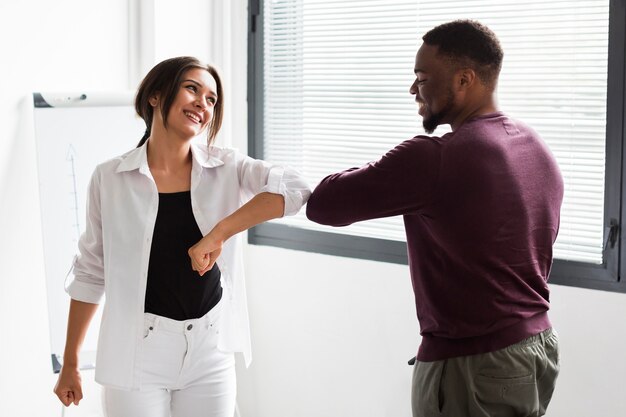 Colleagues touching elbows at work during pandemic to keep distance