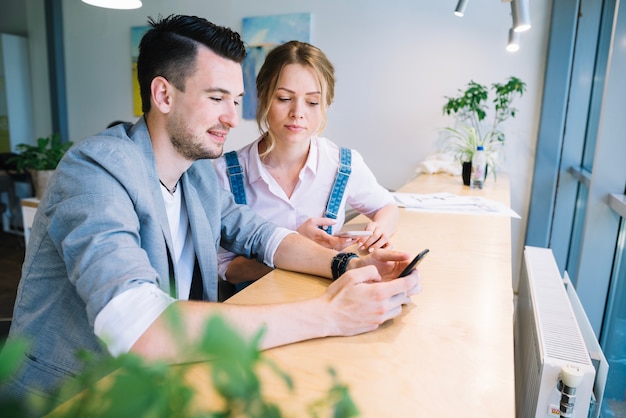 Colleagues using smartphone in office