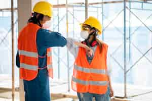 Free photo colleagues with safety equipment touching elbow