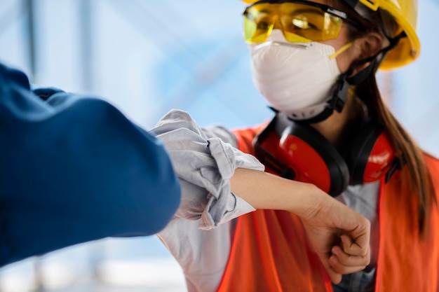 Free photo colleagues with safety equipment touching elbow