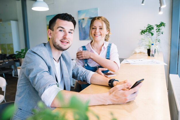 Colleagues with smartphones looking at camera