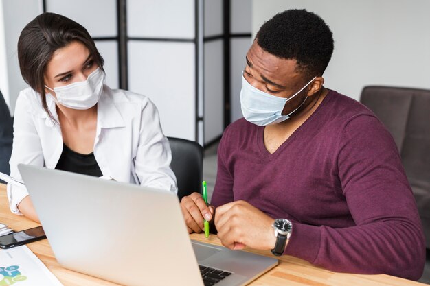 Коллеги работают вместе во время пандемии в офисе в масках