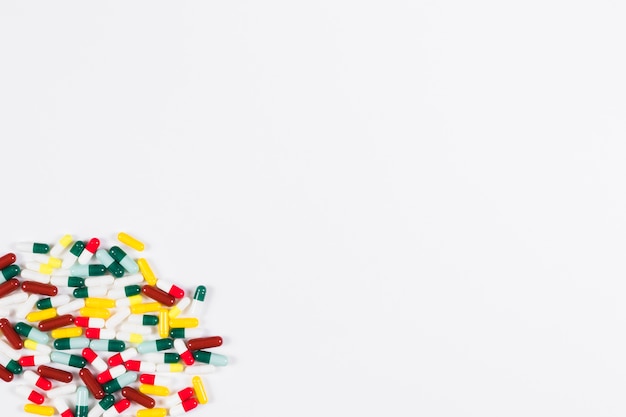 Collection of colorful capsules in the corner of white backdrop
