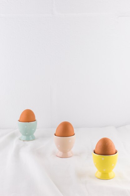 Collection of Easter eggs in cups on light textile